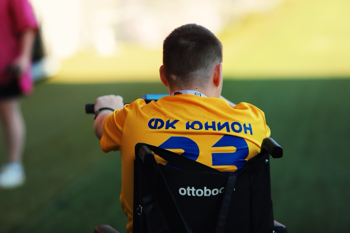 Игрок на коляске в жёлтой футболке ФК Юнион, вид со спины